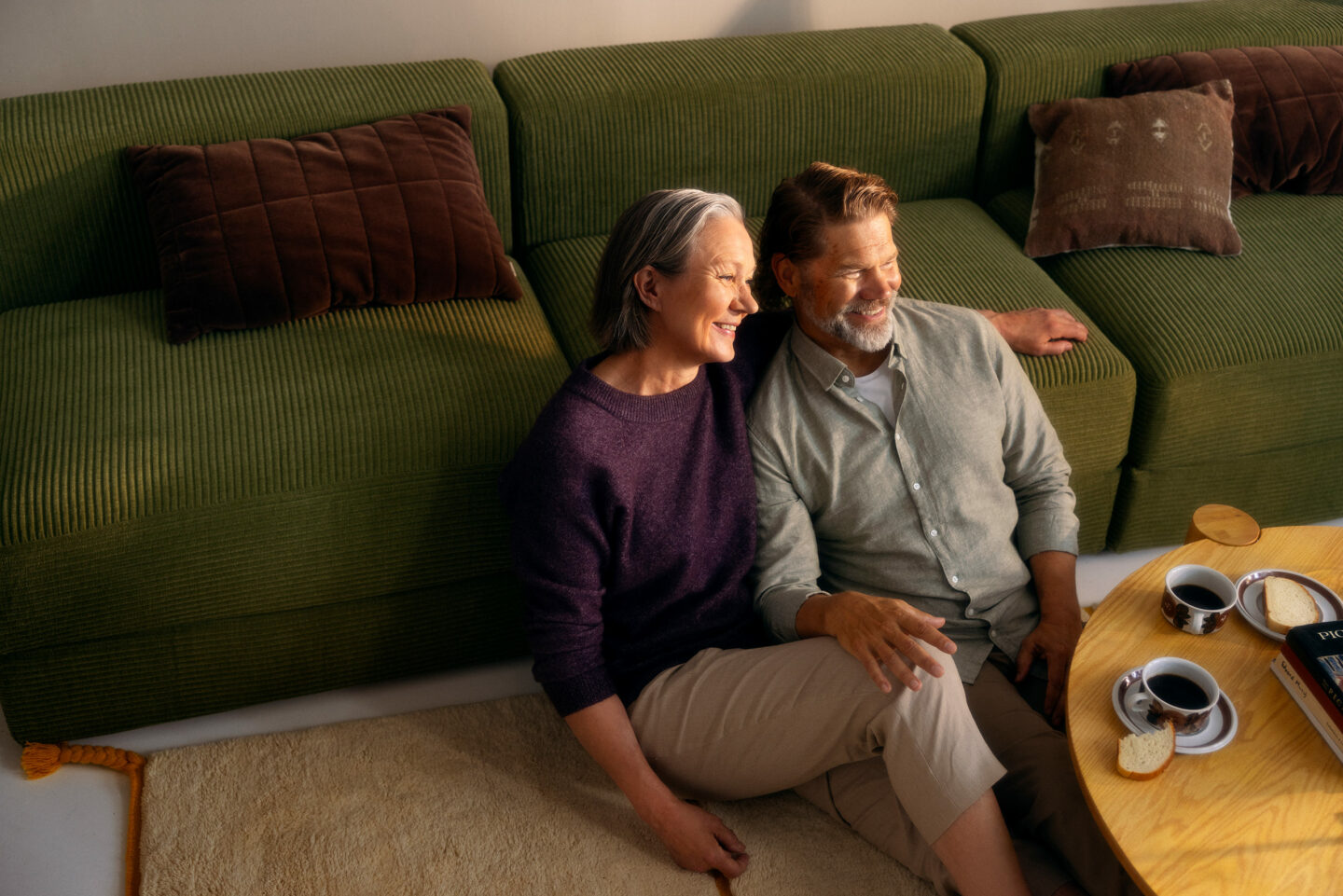 Middle-aged couple sitting on the living room floor.