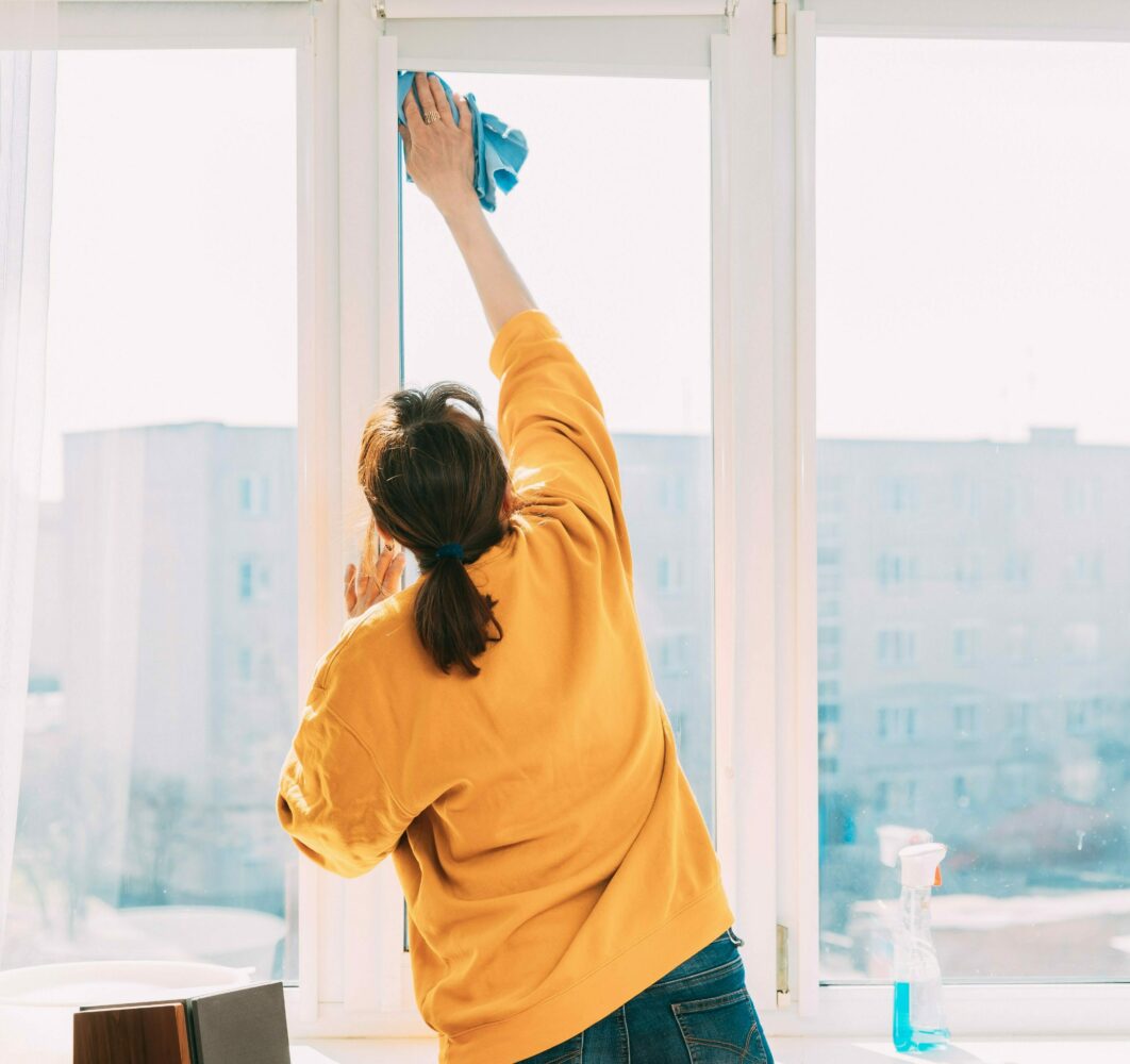 Nainen pesee ikkunaa.