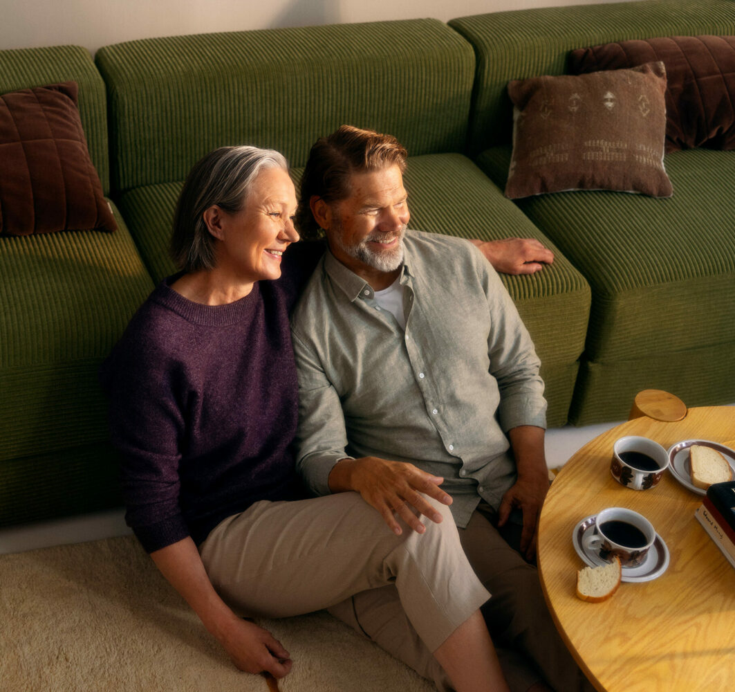 Middle-aged couple sitting in front of a sofa.